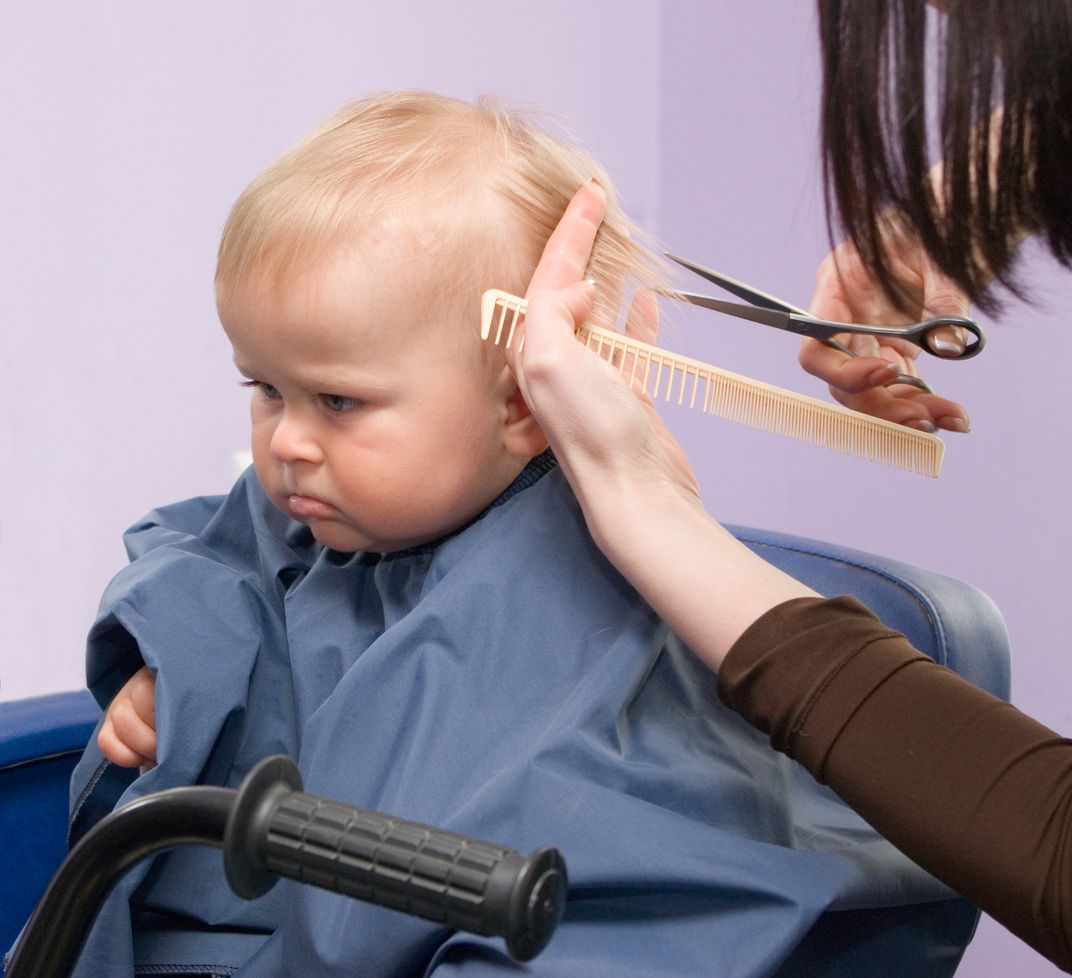 Serious 1-year infant boy during his first haircutting