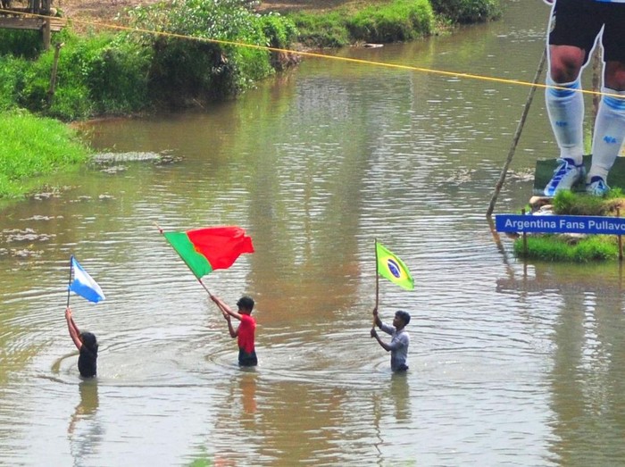Fans wave flags next to the giant cutouts of players from Brazil's Neymar (L), Portuguese Cristiano Ronaldo (C) and Argentine Lionel Messi, erected by football fans in river Cherupuzha at Kozhikode in India's Kerala state on November 7, 2022, ahead of the Qatar 2022 FIFA World Cup football tournament. (Photo by AFP) (Photo by -/AFP via Getty Images)