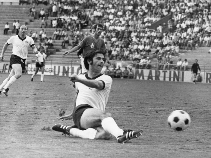 German forward Gerd Mueller (front) slides on the pitch and manages to kick the ball while his fellow teammate German forward Uwe Seeler and Moroccan player Mohamed Maaroufi (back, C) look on from a distance during the 1970 World Cup soccer game Germany against Morocco at the Guanajuato stadium in Leon, Mexico, 3 June 1970. Germany wins the group game 2-1 against Morocco. (Photo by dpa/picture alliance via Getty Images)