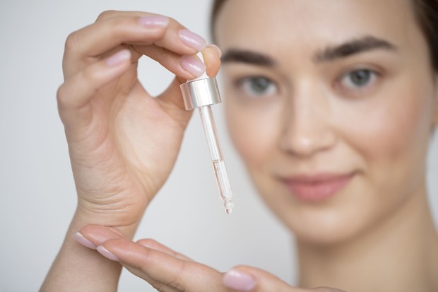 Potret perempuan memegang serum/Foto: freepik.com Potret perempuan memegang serum