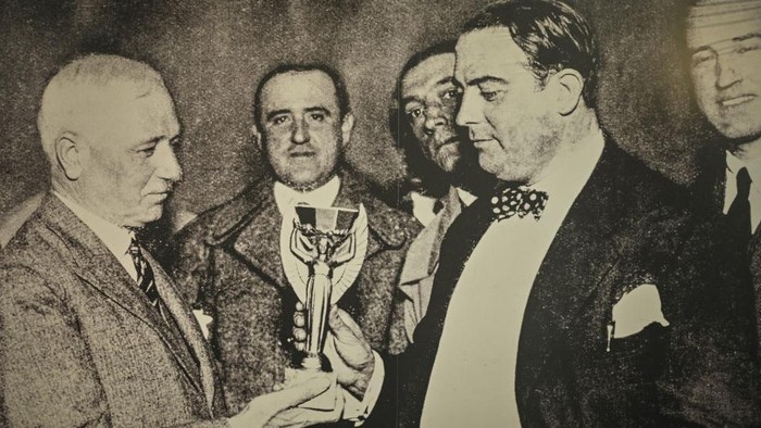 oto momen ketika Jules Rimet menyerahkan trofi kepada Raul Jude yang merupakan presiden Asosiasi Sepak Bola Uruguay saat itu, setelah memenangkan kejuaraan tahun 1930 yang ditaklukkan oleh Uruguay di Stadion Centennial.