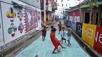 Anak-anak bermain sepak bola di dekat mural bertema Piala Dunia FIFA Qatar di desa Pambusuang, Sulawesi Barat. 