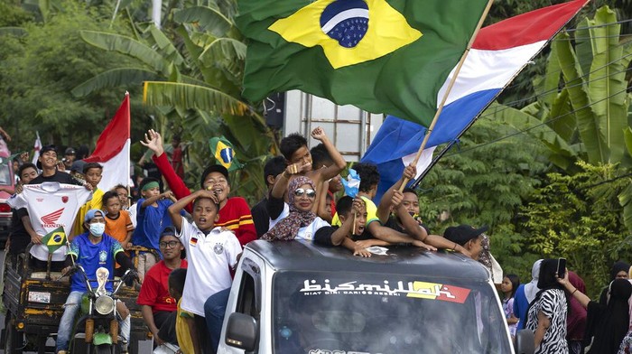 Demam Piala Dunia Mulai Mewabah di Sulawesi Barat Soccer fans wave the flags of participating countries during a parade ahead of the kick-off of the Qatar FIFA World Cup, in Pambusuang village, West Sulawesi, Indonesia, Sunday, Nov. 20, 2022. Qatar prepared Sunday to open the Middle East's first FIFA World Cup before global leaders and soccer fans now pouring into this energy-rich nation after being battered by a regional boycott and international criticism. (AP Photo/Yusuf Wahil)