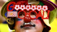 Seorang suporter berdandan seperti badut saat menyaksikan Piala Dunia 2022 di Stadion Al Bayt, Qatar. (Francois Nel/Getty Images)