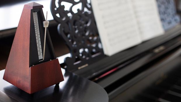 wooden metronome on an old black piano