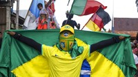 Salah satu supporter mengibarkan bendera dengan menggunakan topi serta penutup muka.