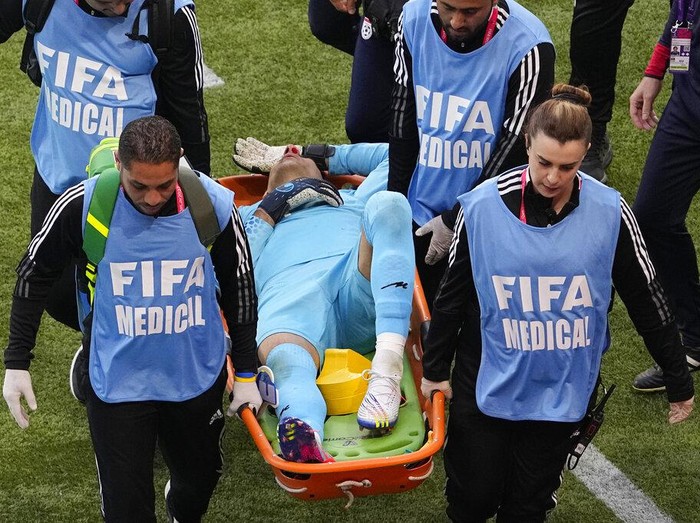 Medics carry Iran's goalkeeper Alireza Beiranvand from the pitch after sustaining an injury during the World Cup group B soccer match between England and Iran at the Khalifa International Stadium in Doha, Qatar, Monday, Nov. 21, 2022. (AP Photo/Pavel Golovkin)