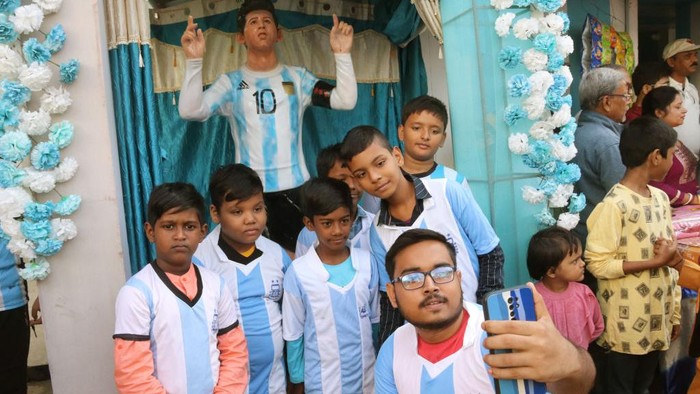 Penggemar Argentina selfie dengan latar patung Lionel Messi di dekat Kolkata, Minggu (20/11/2022).