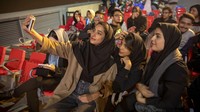 Supporter perempuan Iran mengabadikan momennya saat menonton pertandingan antara Iran dan Inggris di layar lebar di Tehran book Garden, Iran, Senin (21/11/2022). (Kontributor#072019/Getty Images)