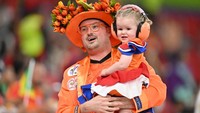 Suporter Belanda menggendong anaknya menggunakan kostum yang bikin gemes saat menonton pertandingan sepak bola Grup A Piala Dunia 2022 Qatar antara Senegal dan Belanda di Stadion Al-Thumama di Doha, Senin (21/11/2022). (GLYN KIRK/Getty Images)