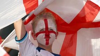Fans Inggris mengecat wajahnya menyerupai bendera Inggris berada di tribun saat menyaksikan pertandingan Grup B Piala Dunia FIFA 2022 antara Inggris dan Iran di Khalifa International Stadium di Doha, Qatar, Senin (21/11/2022). (Evrim Aydin/Getty Images)