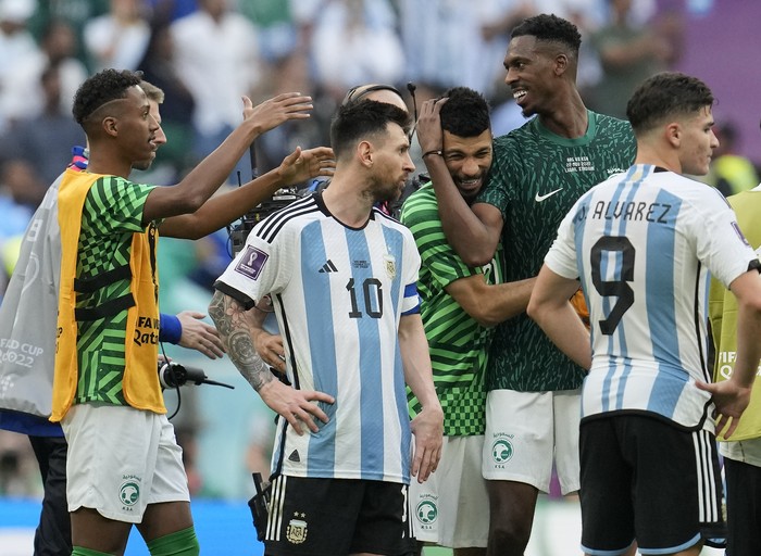 Argentinas Lionel Messi standing beside Saudi Arabias players celebrating after winning the World Cup group C soccer match between Argentina and Saudi Arabia at the Lusail Stadium in Lusail, Qatar, Tuesday, Nov. 22, 2022. (AP Photo/Natacha Pisarenko)