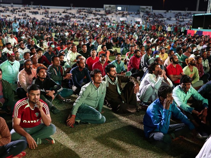Soccer Football - FIFA World Cup Qatar 2022 - Migrant workers watch Qatar v Ecuador - Doha, Qatar - November 20, 2022 Migrant workers gesture during the half time show REUTERS/Marko Djurica