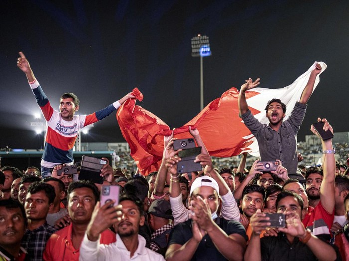 Soccer Football - FIFA World Cup Qatar 2022 - Migrant workers watch Qatar v Ecuador - Doha, Qatar - November 20, 2022 Migrant workers gesture during the half time show REUTERS/Marko Djurica