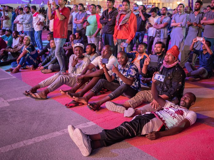 Soccer Football - FIFA World Cup Qatar 2022 - Migrant workers watch Qatar v Ecuador - Doha, Qatar - November 20, 2022 Migrant workers gesture during the half time show REUTERS/Marko Djurica