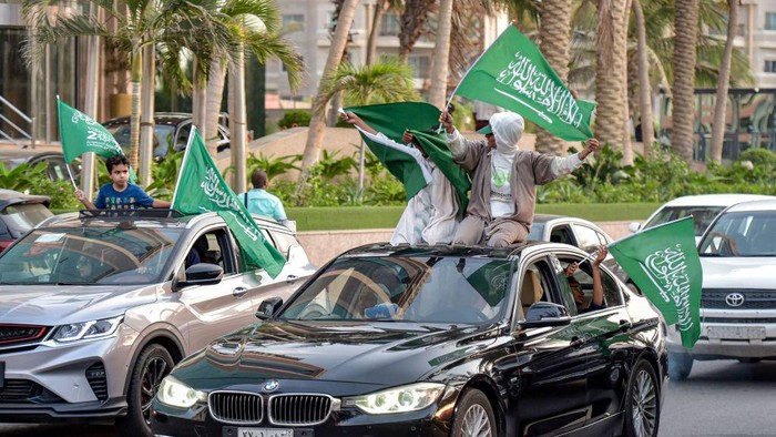 Saudi football fans wave their countrys flags from vehicles as they celebrate their win over Argentina in the Qatar 2022 World Cup, in the capital Riyadh on November 22, 2022. - Disbelieving Saudis formed impromptu dance circles and waved the sword-emblazoned national flag from the windows of speeding cars in Riyadh on November 22 after their teams sensational win over Lionel Messis Argentina. As the final whistle blew in the group-stage shocker with a 2-1 scorecard that ended Argentinas 36-match unbeaten streak, fans watching on a big screen at a stadium in the capital Riyadh sent shisha pipes flying as they rushed to celebrate. (Photo by Amer HILABI / AFP) (Photo by AMER HILABI/AFP via Getty Images)