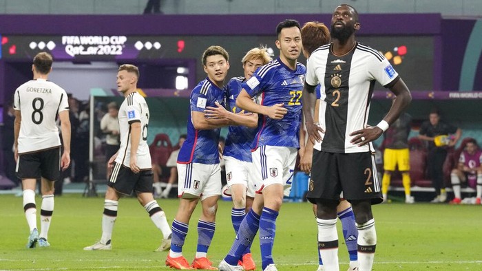 Germanys Antonio Ruediger is dejected as Japan players celebrate at the end of the World Cup group E soccer match between Germany and Japan, at the Khalifa International Stadium in Doha, Qatar, Wednesday, Nov. 23, 2022. Japan won 2-1.(AP Photo/Eugene Hoshiko)