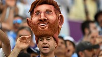 Pendukung Argentina mengenakan topi berbentuk kepala Lionel Messi di Stadion Lusail. (Robert Michael/Getty Images)  