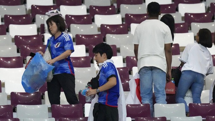 Salut! Suporter Jepang Punguti Sampah di Stadion Piala Dunia Japan supporters clean the stands at the end of the World Cup group E soccer match between Germany and Japan, at the Khalifa International Stadium in Doha, Qatar, Wednesday, Nov. 23, 2022. Japan won 2-1.(AP Photo/Eugene Hoshiko)