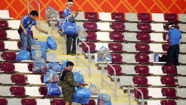 DOHA, QATAR - NOVEMBER 23: Japanese fans clear rubbish from the stands during the FIFA World Cup Qatar 2022 Group E match between Germany and Japan at Khalifa International Stadium on November 23, 2022 in Doha, Qatar. (Photo by Alex Grimm/Getty Images)