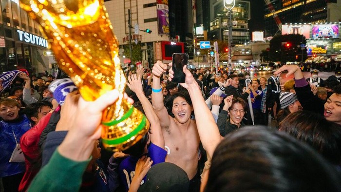 People celebrate at Shibuya crossing in Tokyo, as Japan's national soccer team won against Germany in the World Cup in Qatar, early Thursday, Nov. 24, 2022.(Kyodo News via AP)