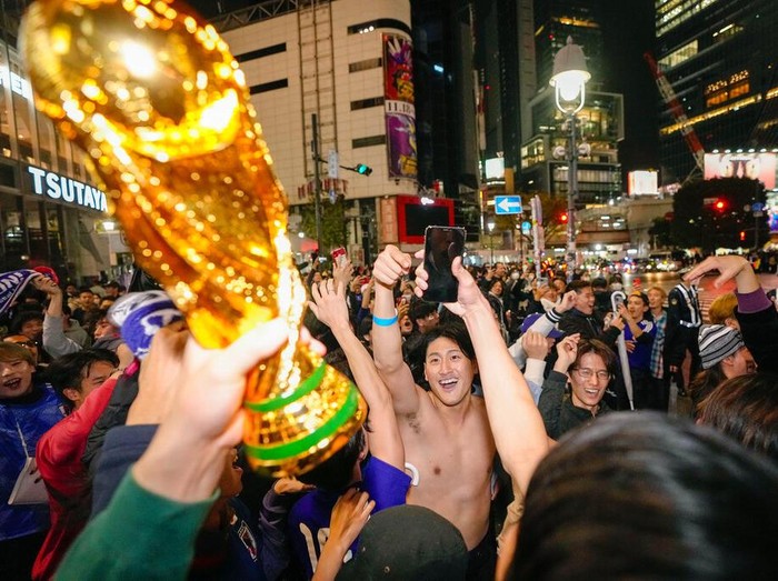 People celebrate at Shibuya crossing in Tokyo, as Japan's national soccer team won against Germany in the World Cup in Qatar, early Thursday, Nov. 24, 2022.(Kyodo News via AP)