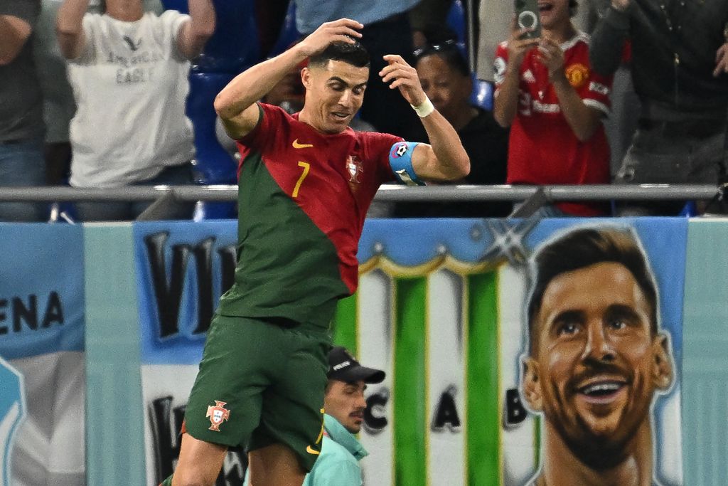 TOPSHOT - Portugal's forward #07 Cristiano Ronaldo celebrates after scoring his team's first goal from the penalty spot as a banner depicting Argentine forward Lionel Messi is seen at the back during the Qatar 2022 World Cup Group H football match between Portugal and Ghana at Stadium 974 in Doha on November 24, 2022. (Photo by MANAN VATSYAYANA / AFP) (Photo by MANAN VATSYAYANA/AFP via Getty Images)