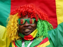 Seorang suporter timnas Kamerun tampil dengan rambut warna-warni dan membentangkan bendera negara tersebut kala mendukung timnas kebanggaannya Kamerun saat melawan Swiss pada pertandingan Grup G Piala Dunia 2022, Kamis (24/11/2022). Matthew Ashton/AMA/Getty Images  