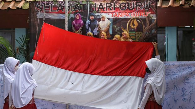 Sejumlah siswa mengibarkan bendera Merah Putih saat upacara Hari Guru di SDN Pondok Cina 1, Depok, Jawa Barat, Jumat (25/11/2022). Siswa SDN Pondok Cina 1 tetap memperingati hari guru meski para guru tidak hadir ke sekolah terhitung sejak Senin (14/11) akibat polemik relokasi sekolah menjadi masjid raya. ANTARA FOTO/Asprilla Dwi Adha/aww.