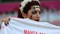 Beberapa pendukung Iran membawa baju bertuliskan Mahsa Amini. Mahsa Amini (22) adalah perempuan Iran yang meninggal pada 16 September 2022 setelah ditangkap polisi moral Iran di Teheran karena jilbabnya dianggap tak pantas.