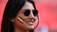 Seorang pendukung Iran tersenyum dengan gambar bendera Iran di pipinya.