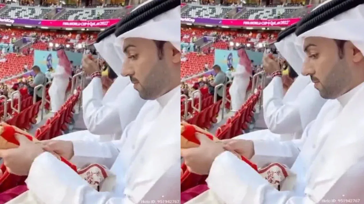 Seorang pria berpakaian gamis putih memamerkan sejumlah isi goodie bag nonton Piala Dunia Qatar 2022.