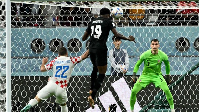 Canada's forward #19 Alphonso Davies heads the ball to score his team's first goal past Croatia's goalkeeper #01 Dominik Livakovic during the Qatar 2022 World Cup Group F football match between Croatia and Canada at the Khalifa International Stadium in Doha on November 27, 2022. (Photo by Patrick T. FALLON / AFP) (Photo by PATRICK T. FALLON/AFP via Getty Images)