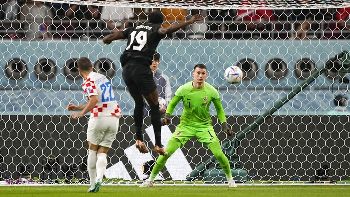 Canada's Alphonso Davies, top, heads the ball to score the opening goal past Croatia's goalkeeper Dominik Livakovic, right, during the World Cup group F soccer match between Croatia and Canada, at the Khalifa International Stadium in Doha, Qatar, Sunday, Nov. 27, 2022. (AP Photo/Martin Meissner)