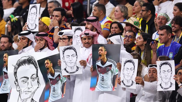 AL KHOR, QATAR - NOVEMBER 27: Local fans holding pictures and posters of Mesut Ozil during the FIFA World Cup Qatar 2022 Group E match between Spain and Germany at Al Bayt Stadium on November 27, 2022 in Al Khor, Qatar. (Photo by Robbie Jay Barratt - AMA/Getty Images)