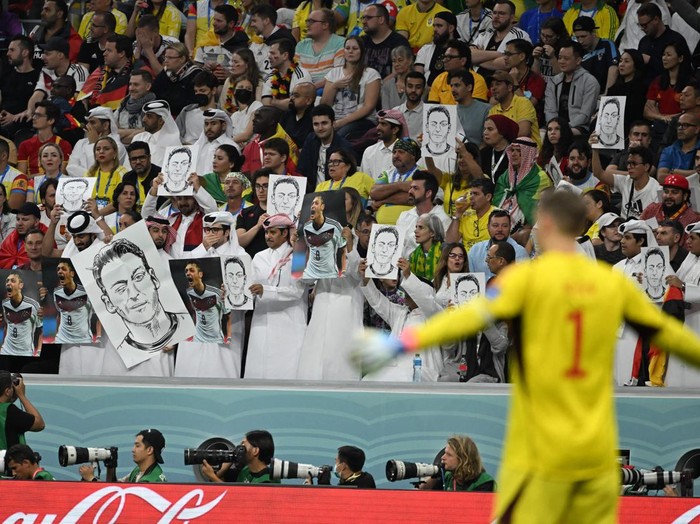 People on the stands hold portraits of German football player Mesut Ozil during the Qatar 2022 World Cup Group E football match between Spain and Germany at the Al-Bayt Stadium in Al Khor, north of Doha on November 27, 2022. (Photo by Ina Fassbender / AFP) (Photo by INA FASSBENDER/AFP via Getty Images)