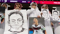 Tidak hanya membawa foto dan gambar Oezil, beberapa fans yang mengenakan ghutra atau penutup kepala khas Qatar ini juga menunjukkan gestur tutup mulut. (Foto: Getty Images/Sebastian Frej/MB Media)
