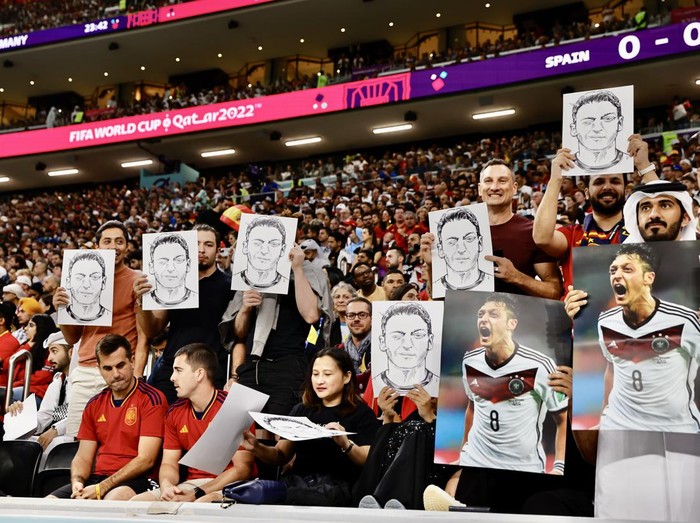 AL KHOR, QATAR - NOVEMBER 27: Fans hold photos and posters of Mesut Ozil of Medipol Basaksehir during the FIFA World Cup Qatar 2022 Group E match between Spain and Germany at Al Bayt Stadium on November 27, 2022 in Al Khor, Qatar. (Photo by Mohammed Dabbous/Anadolu Agency via Getty Images)