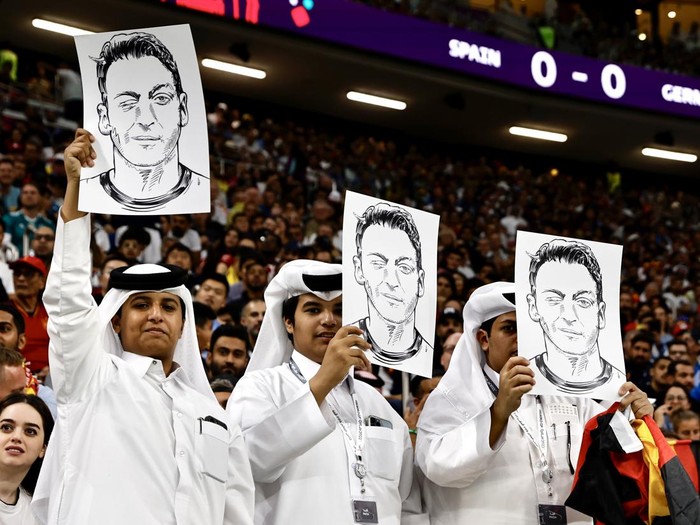 AL KHOR, QATAR - NOVEMBER 27: Fans hold photos and posters of Mesut Ozil of Medipol Basaksehir during the FIFA World Cup Qatar 2022 Group E match between Spain and Germany at Al Bayt Stadium on November 27, 2022 in Al Khor, Qatar. (Photo by Mohammed Dabbous/Anadolu Agency via Getty Images)