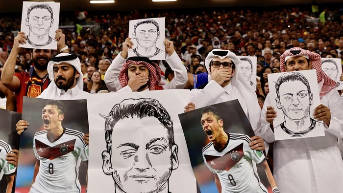 AL KHOR, QATAR - NOVEMBER 27: Fans hold photos and posters of Mesut Ozil of Medipol Basaksehir during the FIFA World Cup Qatar 2022 Group E match between Spain and Germany at Al Bayt Stadium on November 27, 2022 in Al Khor, Qatar. (Photo by Mohammed Dabbous/Anadolu Agency via Getty Images)