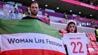Aksi protes juga datang dari fans timnas Iran. Mereka membawa bendera bertuliskan Woman Life Freedom. Aksi protes ini dipicu oleh kematian Mahsa Amini, seorang perempuan Kurdi berusia 22 tahun yang tewas di tangan polisi moral karena tidak mengenakan hijab. Kasus tersebut dibawa dan disuarakan dalam ajang Piala Dunia agar kasus segera terselesaikan. Harry Langer/DeFodi Images/Getty Images  