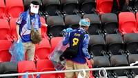 Saat suporter Kosta Rika melampiaskan euforia atas kemenangan pertandingan tersebut, suporter Jepang memilih untuk bersih-bersih stadion. Reuters/Marko Djurica  