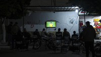 Warga Palestina menyaksikan siaran langsung pertandingan sepak bola grup G Piala Dunia antara Brasil dan Swiss yang dimainkan di Qatar, di jalan di Rafah, Jalur Gaza selatan.  