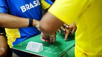 Helio membimbing tangan Carlos di atas papan kayu tersebut sesuai dengan pertandingan laga Piala Dunia yang ia saksikan lewat tv.  
