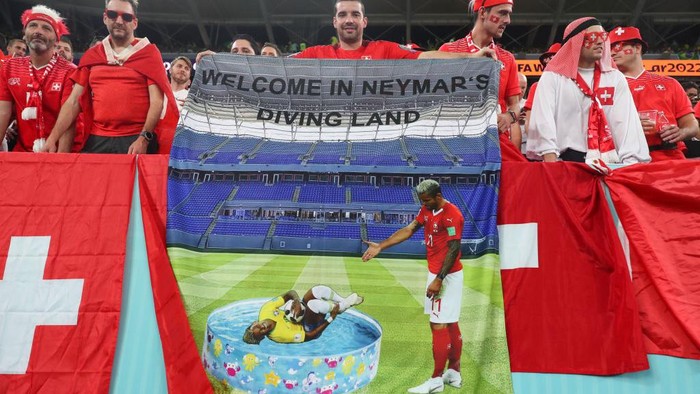 DOHA, QATAR - NOVEMBER 28: Fans of Switzerland holding a flag that reads Welcome To Neymars Diving Land during the FIFA World Cup Qatar 2022 Group G match between Brazil and Switzerland at Stadium 974 on November 28, 2022 in Doha, Qatar. (Photo by Robbie Jay Barratt - AMA/Getty Images)