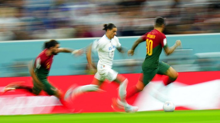 Uruguays Darwin Nunez runs with the ball chased by Portugals Ruben Neves, left, and Joao Cancelo, right, during the World Cup group H soccer match between Portugal and Uruguay, at the Lusail Stadium in Lusail, Qatar, Monday, Nov. 28, 2022. (AP Photo/Petr David Josek)