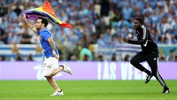 Petugas keamanan berlari mengejar seorang pria yang membawa bendera pelangi memasuki lapangan saat pertandingan Grup H antara Portugal vs Uruguay di Stadion Lusail, Qatar, Senin (28/11/2022). (Francois Nel/Getty Images)  