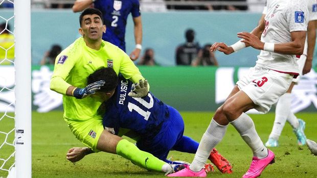 Christian Pulisic of the United States, center, collides with Iran's goalkeeper Alireza Beiranvand, left, after scoring his sides first goal during the World Cup group B soccer match between Iran and the United States at the Al Thumama Stadium in Doha, Qatar, Tuesday, Nov. 29, 2022. (AP Photo/Manu Fernandez)