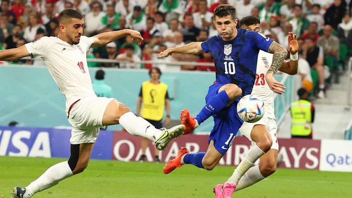 29 November 2022, Qatar, Doha: Soccer, 2022 World Cup in Qatar, Iran - USA, preliminary round, Group B, Matchday 3 at Al-Thumama Stadium in Doha, Christian Pulisic (M) of the USA scores against Iran's Majid Hosseini (l) and Ramin Rezaeian to make it 0-1. Photo: Christian Charisius/dpa (Photo by Christian Charisius/picture alliance via Getty Images)