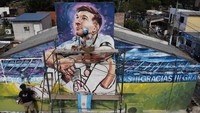 Seniman Marlene Zuriaga dan Lisandro Urteaga terlihat sedang menyelesaikan detail mural yang menggambarkan bintang sepak bola Argentina bernomor punggung 10 tersebut.  